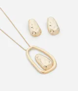 Conjunto de collar con cadena fina y dije con forma orgánica y aros tipo botón con forma orgánica, ambos en metal dorado con textura irregular.