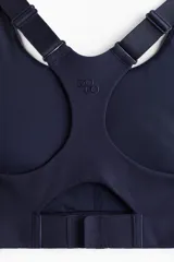 Top deportivo azul marino de tejido funcional con tecnología ShapeMove™ y DryMove™. Ofrece ajuste ceñido, soporte óptimo y absorción de sudor. Cuenta con copas forradas con relleno extraíble, breteles anchos ajustables, espalda nadadora de malla con abertura y cierre de corchetes trasero.
