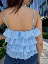 Blusa color amarillo manteca con breteles finos, escote en V con detalle de encaje y volados en capas.