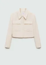 Chaqueta corta color crema con rayas verticales finas, cuello camisero, cierre frontal con botones ocultos, manga larga y dos bolsillos de parche en la parte delantera.