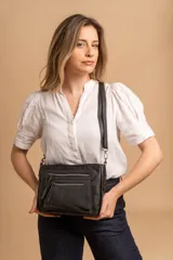 Bandolera de simil cuero color negro con detalles en nobuck. Posee cierre principal, además de cierres adicionales en la parte delantera y trasera.