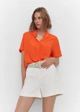 Camisa blanca de viscosa con cuello camisero, manga corta, bolsillo de parche en el pecho y corte oversize.