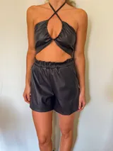 Conjunto de blazer y short de cuero sintético negro. El blazer es de corte clásico con solapas y mangas largas. El short es de tiro alto con cintura elastizada.