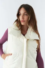 Chaleco blanco con cuello alto y bolsillos laterales.