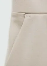 Pantalón de vestir color beige, de corte recto y tiro alto. Presenta cintura elastizada y bolsillos laterales.