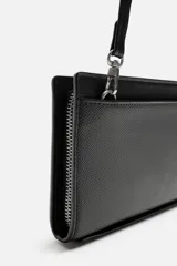 Bandolera negra rectangular con textura grabada. Tiene un compartimento principal con cierre de cremallera, un bolsillo interior con cremallera y un bolsillo simple. El asa de hombro es ajustable y extraíble.