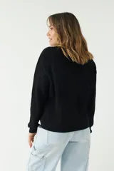 Sweater negro de punto con textura acanalada, cuello redondo y corte relajado.