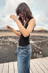 Body entallado color marrón oscuro con escote pronunciado en pico y manga sisa. Cierre en la parte inferior con botones a presión.