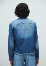 Campera corta de denim azul con efecto desgastado. Tiene cuello clásico, cierre frontal con botones, dos bolsillos delanteros y terminaciones desflecadas.