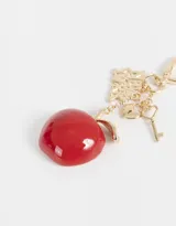 Llavero con dije de manzana roja, dije con la frase "New York" y dije de oso de peluche color borgoña con moño de cinta.