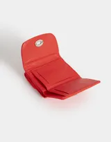 Billetera cuadrada de cuerina color negro con cierre de broche metálico. Cuenta con compartimentos para tarjetas y billetes.