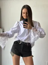 Camisa blanca de mangas largas abullonadas con puños de encaje y cuello clásico.