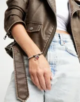 Pulsera de cuero marrón con cuentas plateadas y dijes colgantes: un dije de corazón calado y un dije de cristal de murano color borgoña.