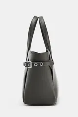 Bolso mini shopper de cuero sintético color gris oscuro, con doble asa de mano y detalles de ojales metálicos en los laterales. Incluye asa extraíble para llevar como bandolera y cierre magnético.