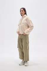 Buzo de polar tipo sherpa en color crudo, con cuello alto y cierre frontal parcial. Presenta un bolsillo de parche con cierre en el pecho y mangas largas de calce holgado.