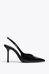 Zapato destalonado acharolado color negro, con tacón fino y punta. Tiene una tira trasera con elástico.