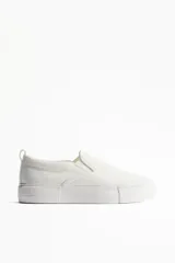 Zapatillas slip-on blancas de lona con elásticos laterales, cuello acolchado y tirador trasero.