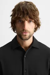 Camisa azul marino slim fit de manga larga con cuello italiano abierto y cierre frontal con botones.
