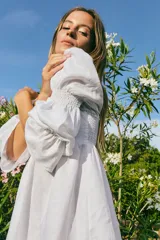 Vestido corto blanco de lino, con escote recto, mangas abullonadas 3/4 con elástico y falda con volado.