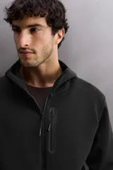 Sudadera con capucha color marrón topo, de corte regular fit, confeccionada en tejido técnico compacto de algodón con elasticidad. Cuenta con cuello subido, manga larga con bolsillo, bolsillos frontales con cierre de cremallera y acabados con rib del mismo tejido.