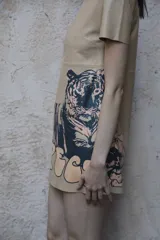 Vestido corto color beige confeccionado en cuero, con escote redondo, manga corta y estampa de tigre y letras en la falda.