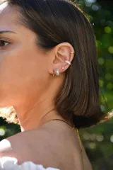 Aros dorados pequeños con forma cuadrada y circonitas negras incrustadas.