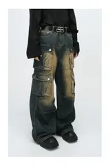 Pantalón de jean ancho (baggy) con lavado oscuro y efecto desgastado en tonos marrones/ocre. Presenta múltiples bolsillos cargo grandes con tapa y botones a presión en las piernas.
