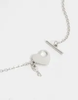 Cadena corta dorada con dije de corazón y llave de metal.