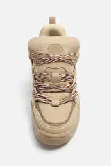 Zapatilla deportiva color beige, estilo skate. Capellada fabricada en combinación de piezas y materiales. Lengüeta acolchada. Detalle de cordones de cuerda. Tirador trasero para facilitar el calce. Suela con volumen y diseño irregular.