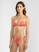 Bikini inferior estilo triángulo confeccionado en tejido reciclado con estampado pinstripe floral en tonos rojos y rosados. Presenta tiras ajustables a los laterales con terminaciones metálicas insignia de Polonio y forro interior.