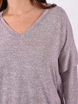 Buzo de tejido melange gris claro, con cuello en V y manga larga. El calce es holgado y el ruedo ajustado con elástico.