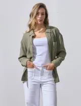 Camisa blanca de algodón con textura arrugada, cuello con solapa, abertura central con botones y bolsillo aplicado en el pecho. Mangas largas con largo regulable mediante presilla y botón.
