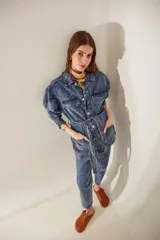 Campera de denim celeste con efecto nevado, corte recto, cuello clásico, cierre frontal con botones metálicos, cuatro bolsillos frontales con solapa y cinturón de la misma tela con hebilla metálica.