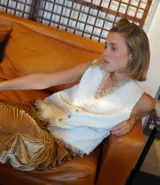 Chaleco color crema con textura brocada y flecos deshilachados en el ruedo.