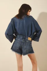 Short de jean de tiro medio, confeccionado en denim rígido azul, con lavado localizado con bigotes y ruedo desflecado.