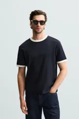 Camiseta azul marino de corte regular, con cuello redondo y mangas cortas. Presenta ribete blanco en cuello y mangas.