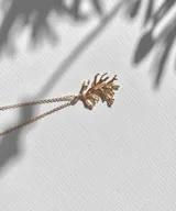 Collar plateado con dije en forma de coral. El dije tiene una textura rugosa y un diseño intrincado que imita la forma natural del coral. La cadena es de eslabones finos y delicados.