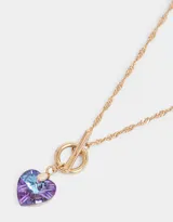 Collar corto dorado con cadena de eslabones retorcidos y dije de corazón de cristal color lila.