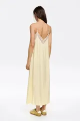 Vestido midi color verde oliva con breteles finos, escote en V y botones frontales. Detalles de encaje blanco en escote, sisas y ruedo.