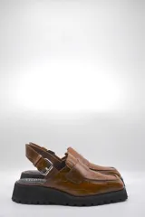Zueco tipo mocasín color marrón con textura croco y tira regulable al talón.