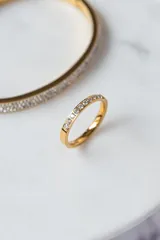 Anillo dorado tipo cintillo con hilera de circonitas engarzadas.