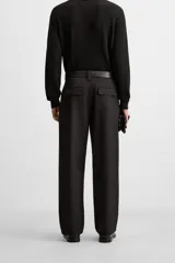 Pantalón negro de corte recto con cinturón de cuero sintético, pliegues frontales, bolsillos laterales y traseros con solapa.