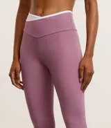Calza deportiva color lila con cintura alta en V bicolor, confeccionada en microfibra ligera.