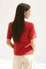 Remera blanca de algodón de corte recto, con cuello redondo y mangas cortas. Presenta detalle de aberturas laterales con ojales metálicos.