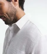 Camisa de manga corta blanca con textura de rayas, cuello inglés y abotonadura frontal.