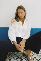 Camisa corta blanca con bordados perforados, cuello solapa, escote pico y manga larga abullonada.