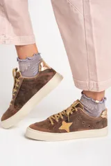 Zapatillas bajas de cuero color marrón con estrella beige en el lateral, cordones color beige y detalle dorado en el talón.