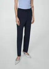 Pantalón de vestir azul marino, de corte recto, con bolsillos laterales y traseros. Se ajusta a la cintura con cinturón de cuero marrón.