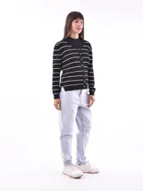 Cárdigan negro con rayas horizontales blancas, cuello en V y botones dorados.