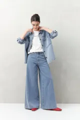 Pantalón de jean celeste de calce ultra wide leg, tiro alto y silueta amplia desde la cadera hasta el bajo. Diseño clásico de cinco bolsillos y cierre con botón metálico y cremallera.